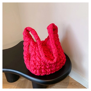 Close-up of quilted fuchsia cloud bag with zipper detail on modern black table