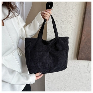 Detail view of black corduroy tote bag with dual front pockets and textured material