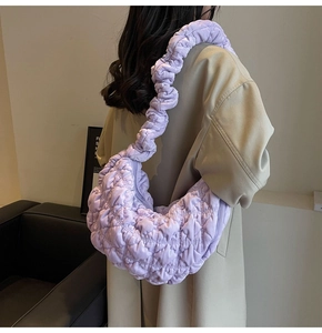 Detail of lavender quilted cloud bag with ruched strap on model in minimalist setting