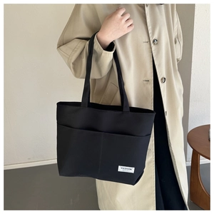 Vista dettagliata della borsa tote in tela nera con tasche frontali ed etichetta