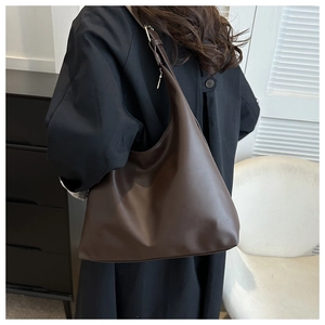 Minimalist dark brown matte PU tote bag worn by a model in a modern interior setting