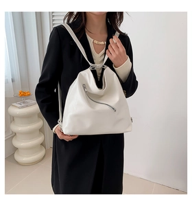 Sac à bandoulière en cuir PU blanc minimaliste avec une fermeture éclair diagonale sur manteau noir
