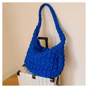 Detail of blue quilted cloud bag with pleated texture on a silver suitcase for travel