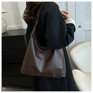 Detail view of large dark brown PU leather Hobo shoulder bag worn by female model