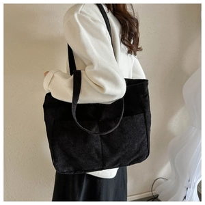 Detail view of large black corduroy tote bag with two front pockets on shoulder