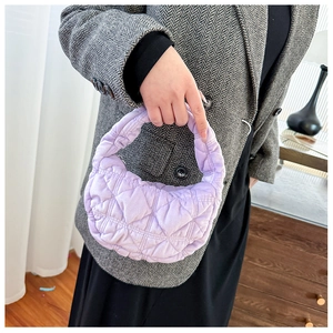 Detail of lavender quilted plush handbag featuring soft rhombohedral stitching and crescent shape