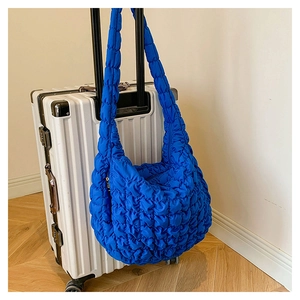 Detail of bright blue quilted bubble hobo bag showing 3D texture and wide shoulder strap