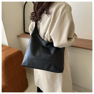 Minimalist black PU leather tote bag with crescent shape and metal zipper on model