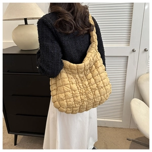 Gros plan d'un sac cabas matelassé jaune moutarde porté par un mannequin dans un intérieur chic