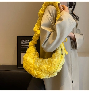 Detailed close-up of yellow quilted velvet handbag with ruched cloud-style shoulder strap