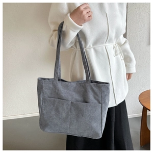 Detailed texture of dark grey corduroy tote bag with dual front pockets and wide straps