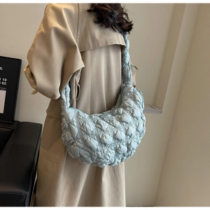 Detailed view of mint green quilted puffer shoulder bag styled with beige trench coat