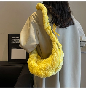 Detail of a bright yellow quilted shoulder bag with ruched handle and metal zipper closure