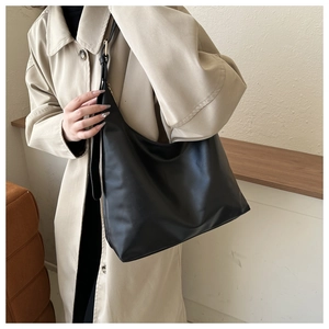 Close-up of a minimalist black PU leather tote bag with elegant gold adjustable buckle