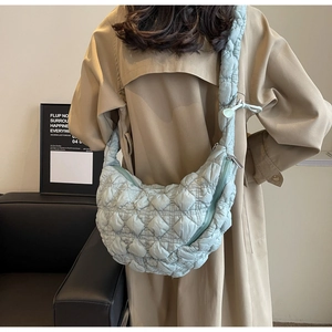 Detail of light green quilted crescent bag with soft embossed texture and matching strap