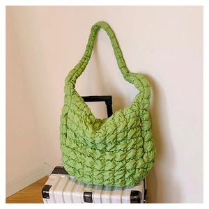 Detail of light green quilted cloud bag with puffer texture on a silver suitcase