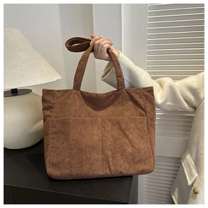 Detail showing brown corduroy tote bag texture with double front pockets and shoulder strap