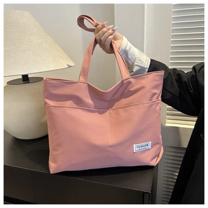 Dettaglio della borsa tote in tela rosa con etichetta in tessuto e tracolla regolabile