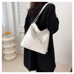 Sac fourre-tout minimaliste en cuir PU blanc avec fermeture éclair diagonale porté à l'épaule