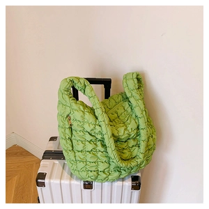 Detail of green quilted puffer tote bag featuring square padding and metal zipper texture