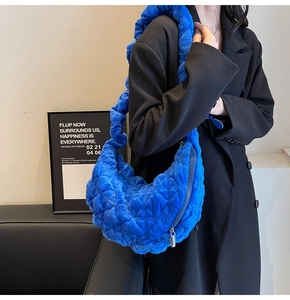Detailed view of quilted blue crescent bag with scrunchie strap and silver zipper closure