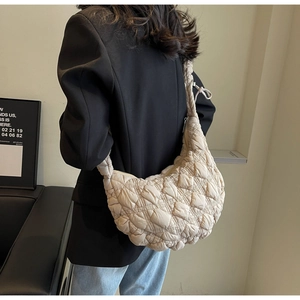 Detailed view of beige quilted cloud bag texture and plush shoulder strap for women