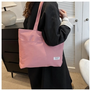 Dettaglio della borsa tote in tela rosa chiaro con etichetta portata a spalla