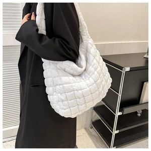 Gros plan d'un sac cabas rembourré blanc avec motif en losanges sur l'épaule d'un modèle
