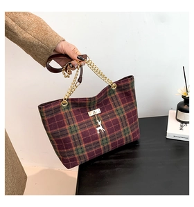 Détail du sac cabas en laine à carreaux rouge et vert avec pendentif cerf doré