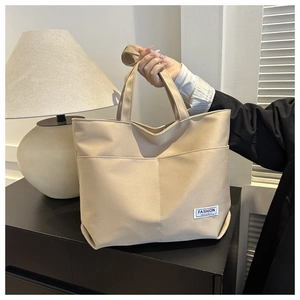 Dettaglio della borsa tote in tela beige minimalista con doppi manici e tasche laterali
