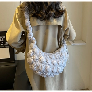 Quilted cloud hobo bag in white with bubble strap carried by model in trench coat