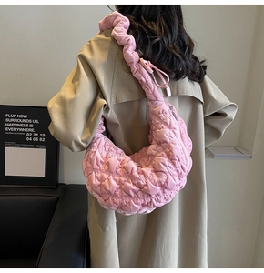 Detail of pink quilted bubble cloud bag with pleated strap on a model wearing trench coat