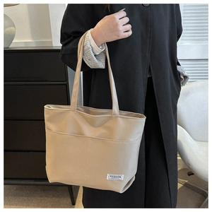 Dettaglio ravvicinato della grande borsa tote in tela con tasche e targhetta