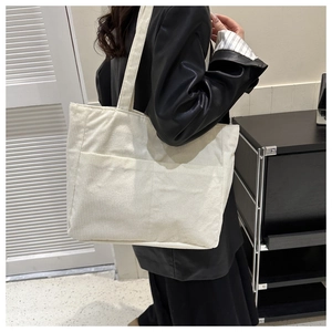 Detail of off-white corduroy tote bag with large front pocket and ribbed texture