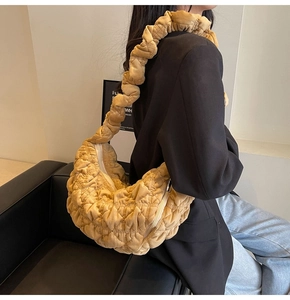 Detail of ginger yellow quilted handbag with ruffled strap on a model wearing black blazer