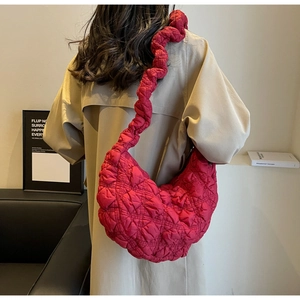 Quilted dark red half-moon shoulder bag with twisted strap on trench coat model