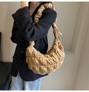 Detail of latte pleated puffy cloud bag featuring quilted texture and soft shoulder strap