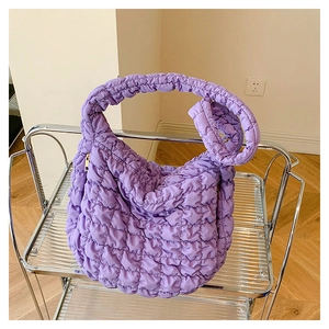 Detail shot of purple quilted cloud bag with puffy texture and gold zipper accents