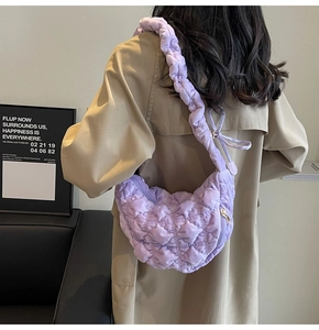 Detail of purple quilted puffer bag featuring pleated shoulder strap and gold metal zipper