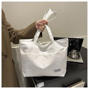 Dettaglio della borsa tote in tela bianca con etichetta Fashion Instinct e grande design