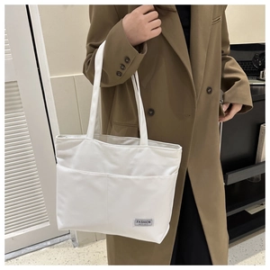 Dettaglio della borsa tote in nylon bianco con tasche frontali ed etichetta tessuta