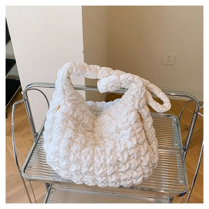 Detailed view of white quilted dumpling bag showing the puffy bubble texture and zip