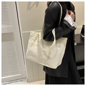 Minimalist beige corduroy tote bag with vertical stripes shown in an indoor fashion lifestyle shot