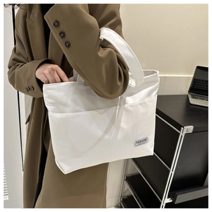 Dettaglio di una borsa tote bianca in tela con logo Fashion Instinct e tasca laterale