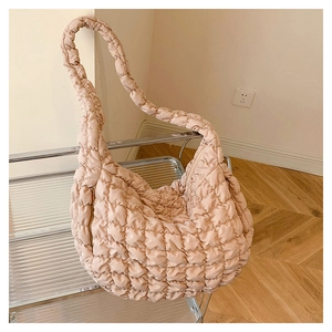 Close-up of beige quilted cloud bag with wavy stitching and metal zipper detail