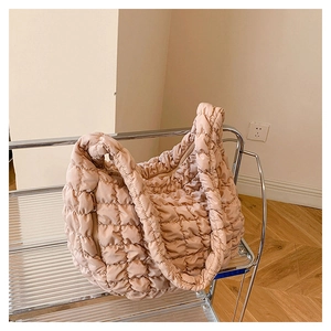 Close-up of beige quilted cloud bag texture and gold zipper detail on shoulder strap