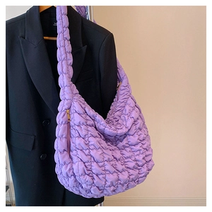 Detail of purple quilted cloud bag with gold side zipper and ruffled strap design
