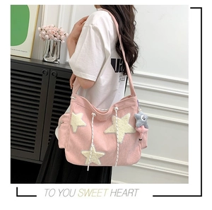 Detail van de roze corduroy tote bag met witte pluche sterren en een sterrenhanger