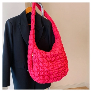 Detail of fuchsia quilted dumpling bag with bubble texture and gold metal zipper on black suit