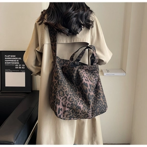 Detail of leopard print canvas tote bag featuring top handles and shoulder strap